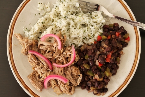 overhead view of a plate of slow-cooked mojo pork with black beans and rice