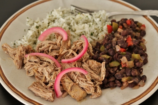 side view of a plate of pulled mojo pork with beans and rice