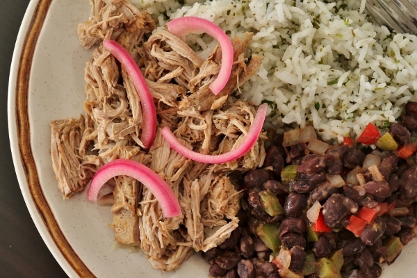 overhead view of chunks of mojo pork served with black beans and rice