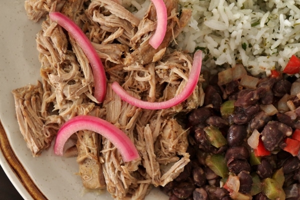 a close up of a plate of slow-cooked mojo pork with pickled onions