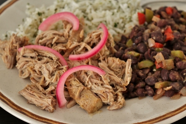 a closeup of slow-cooked pork topped with pickled red onions