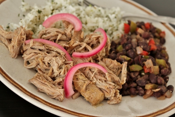 closeup of slow-cooked mojo pork pieces topped with pickled red onions