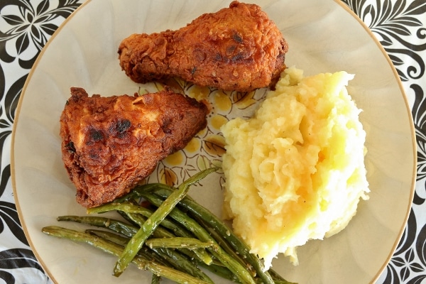 overhead view of a plate of fried chicken with mashed potatoes and green beans