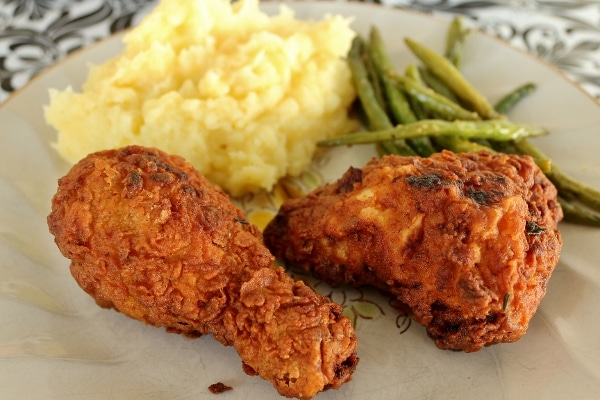 closeup of a plate of fried chicken with mashed potatoes and green beans