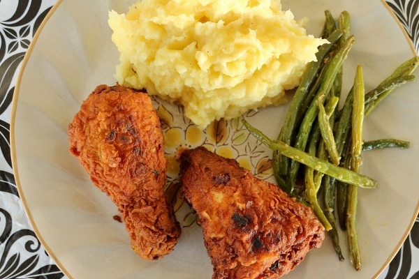 overhead view of a plate of fried chicken with green beans and mashed potatoes