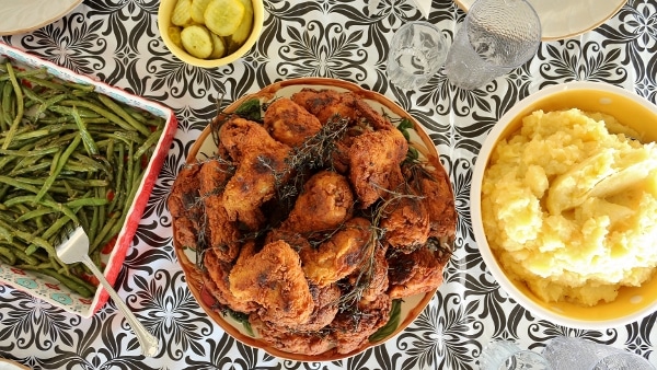 overhead view of a platter of fried chicken with bowls of mashed potatoes and green beans