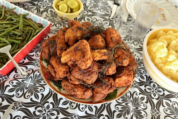 a table set with platters of fried chicken, mashed potatoes, and green beans
