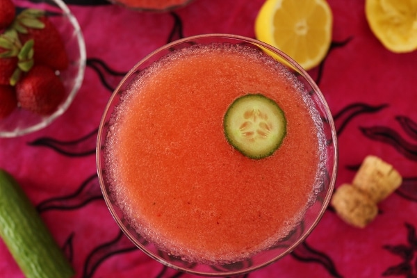 overhead view of a pink cocktail with a slice of cucumber floating on top