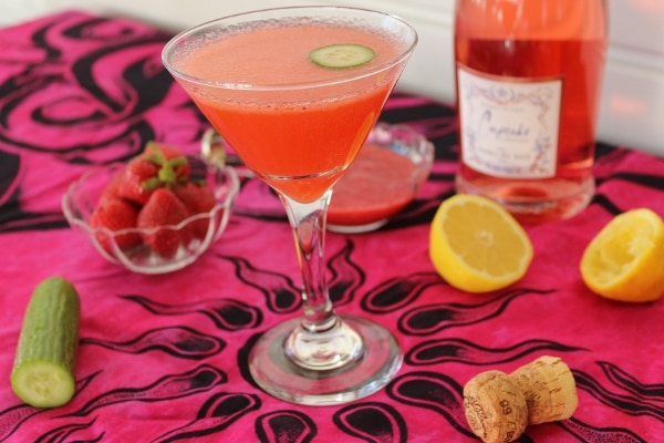 a pink cocktail on a pink tablecloth topped with various ingredients