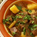 A close up of Burmese beef curry with potatoes, garnished with cilantro.