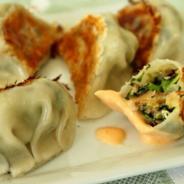 closeup of a half eaten dumpling dipped in sriracha mayo