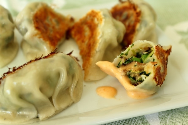 closeup of a half eaten dumpling dipped in sriracha mayo