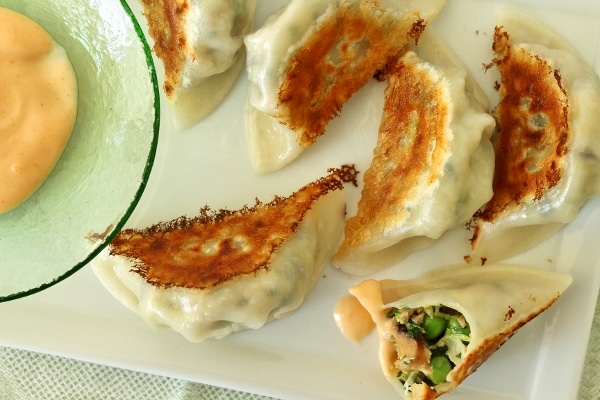 overhead view of a plate of fried dumplings with sriracha dipping sauce