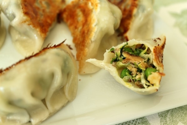 a plate of half eaten dumplings with pea, pea shoot, and mushroom filling