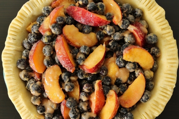 overhead view of an unbaked pie crust filled with blueberry nectarine filling