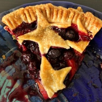 overhead view of a slice of blueberry nectarine pie with star decorations