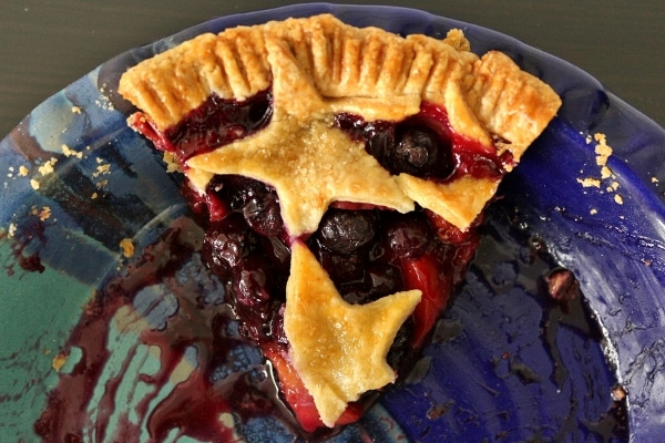 overhead view of a slice of blueberry nectarine pie with star decorations