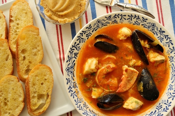 overhead view of a shallow bowl of Provencal fish stew with baguette crisps on the side