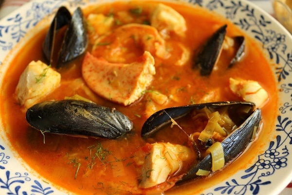 a closeup of a bowl of bouillabaisse with mussels, fish, and lobster