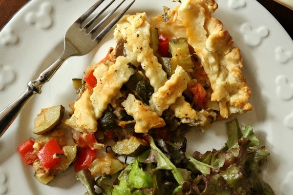 overhead view of a slice of savory ratatouille pie with a side salad