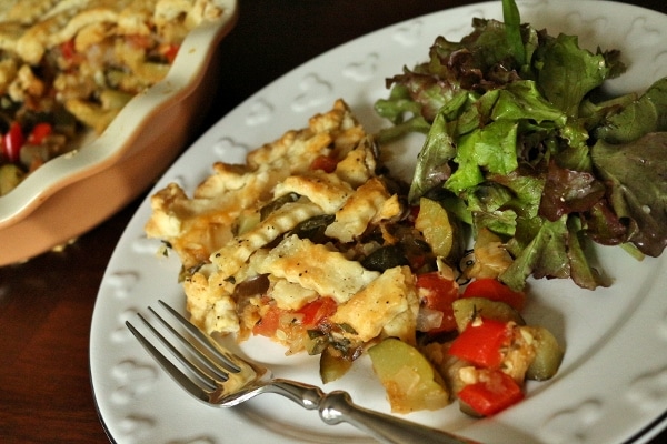 a slice of ratatouille pie with salad on a white plate