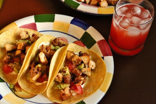 a closeup of 3 chicken tacos on a colorful plate