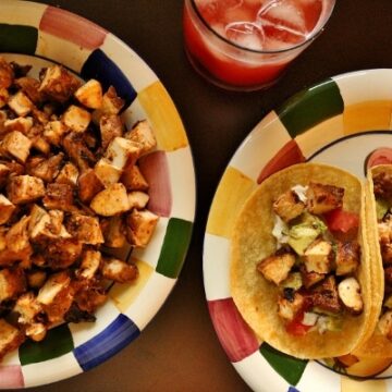 chicken tacos on a colorful plate, a platter of cubed chicken and a strawberry drink