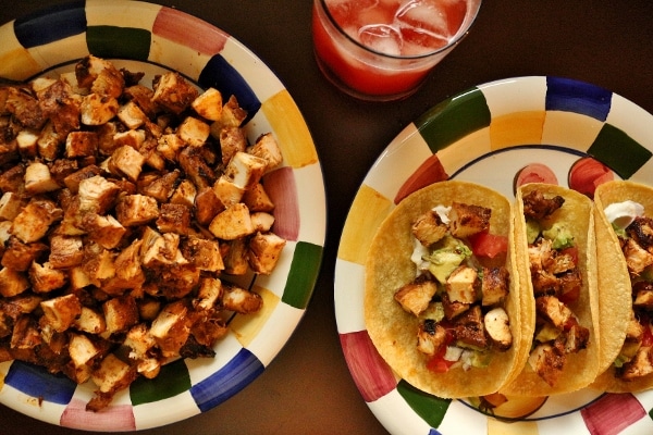 an overhead view of chicken tacos with a platter of cubed chicken on the side