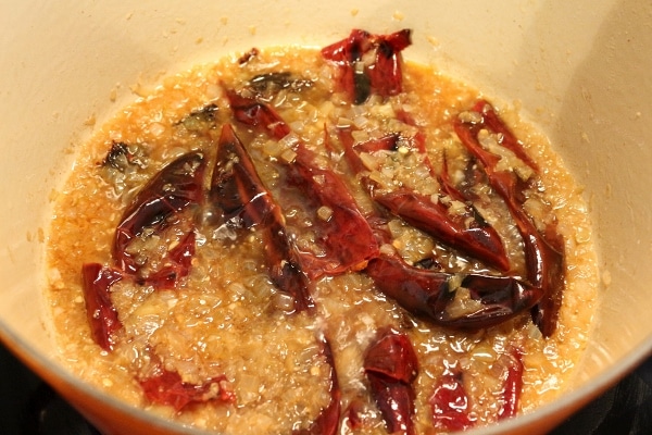 Dried chiles cooking with onions and beer in a Dutch oven