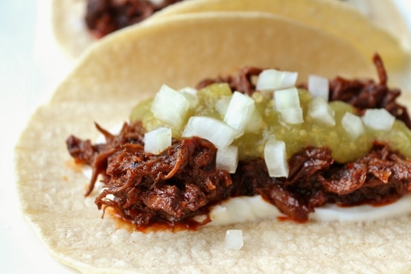 closeup of braised short rib tacos with salsa verde and chopped onions