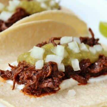 a braised short rib taco in a corn tortilla with salsa verde and chopped onion