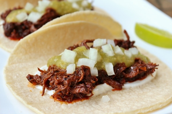 Braised short rib tacos with sour cream, salsa verde, and chopped onions