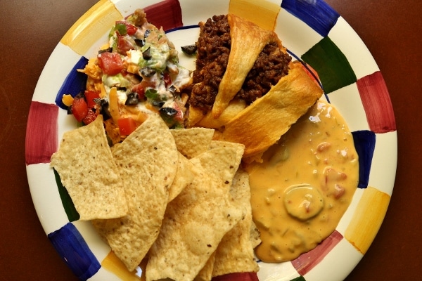 A delicious spread of taco dip, taco ring, chile con queso, and tortilla chips