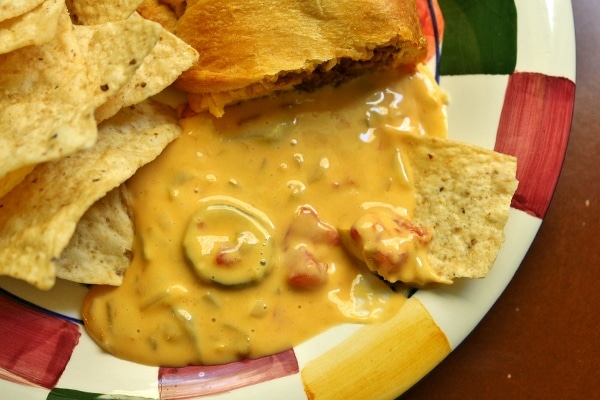 Chile con queso with tortilla chips on a colorful plate