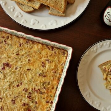hot reuben dip baked in a colorful square dish with toasted rye bread on the side