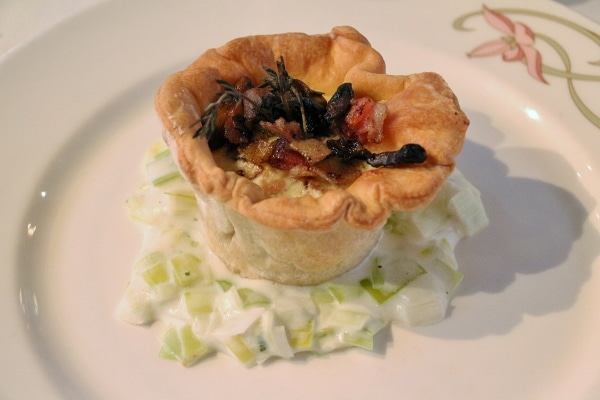 a savory tart over creamed leeks on a plate