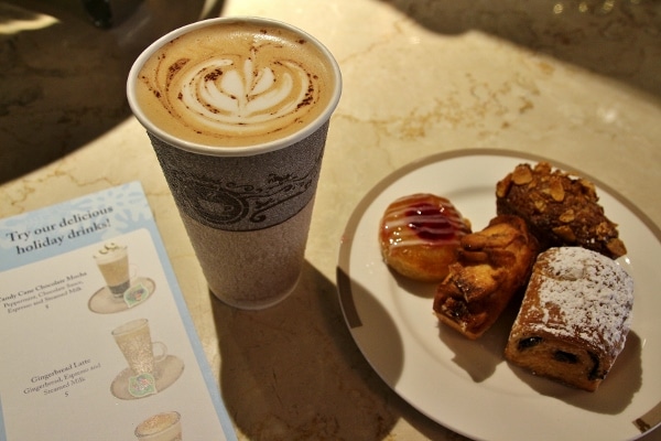 a latte next to a plate of breakfast pastries