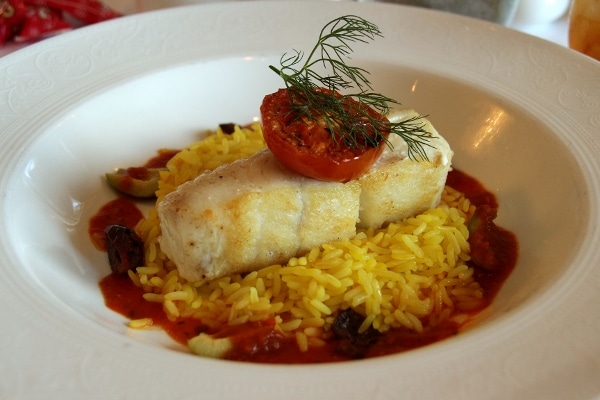 a fillet of fish over yellow rice in a wide bowl