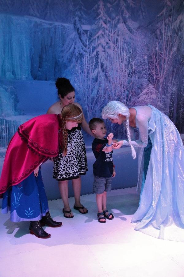 a little boy is showing Anna and Elsa from Frozen his bracelet