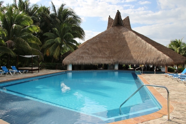 a large pool next to a grass covered hut
