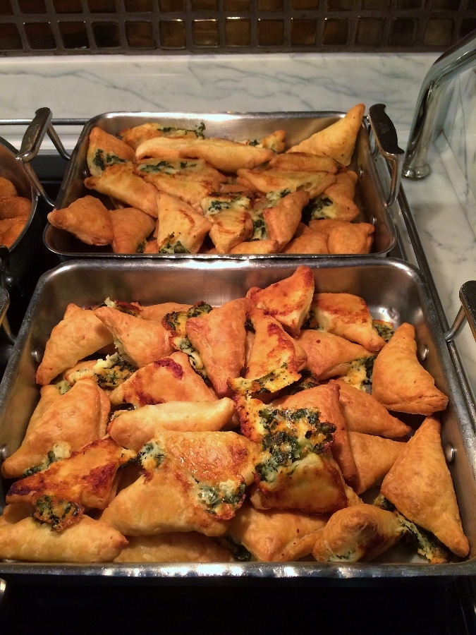 a tray of crispy spinach and cheese triangles on a buffet