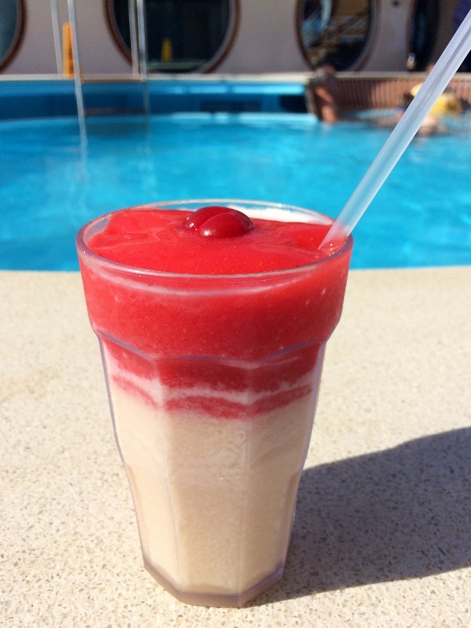 a pina colava frozen cocktail next to a swimming pool