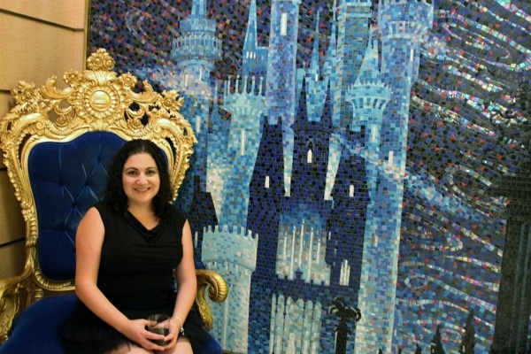 a woman sitting in front of a tile mosaic of Cinderella\'s castle