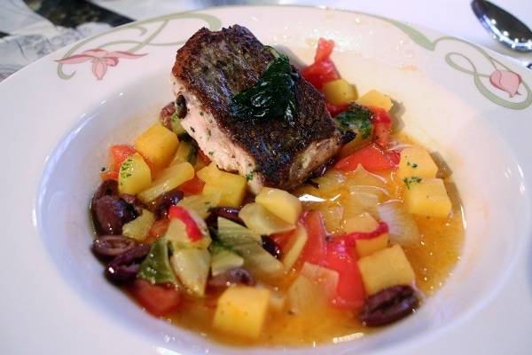 seared fish with vegetables in broth in a shallow bowl