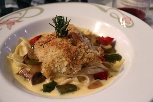 a plate of crusted meat over fettuccine noodles