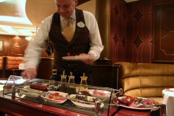 a man assembling an antipasti plate from behind a cart