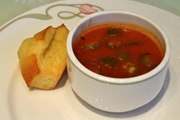 A bowl of soup with a piece of cornbread on the side