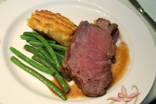 A plate of roast beef with green beans