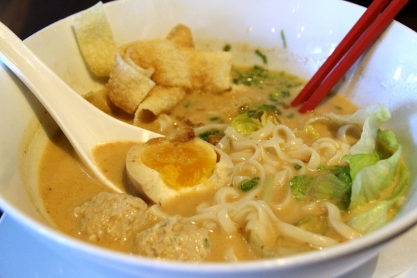 a bowl of laksa noodles with a hard-boiled egg and meatballs