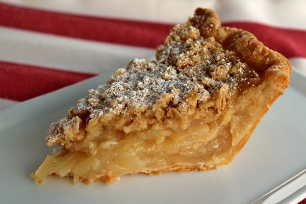 A close up of a slice of pear ginger pie on a white plate